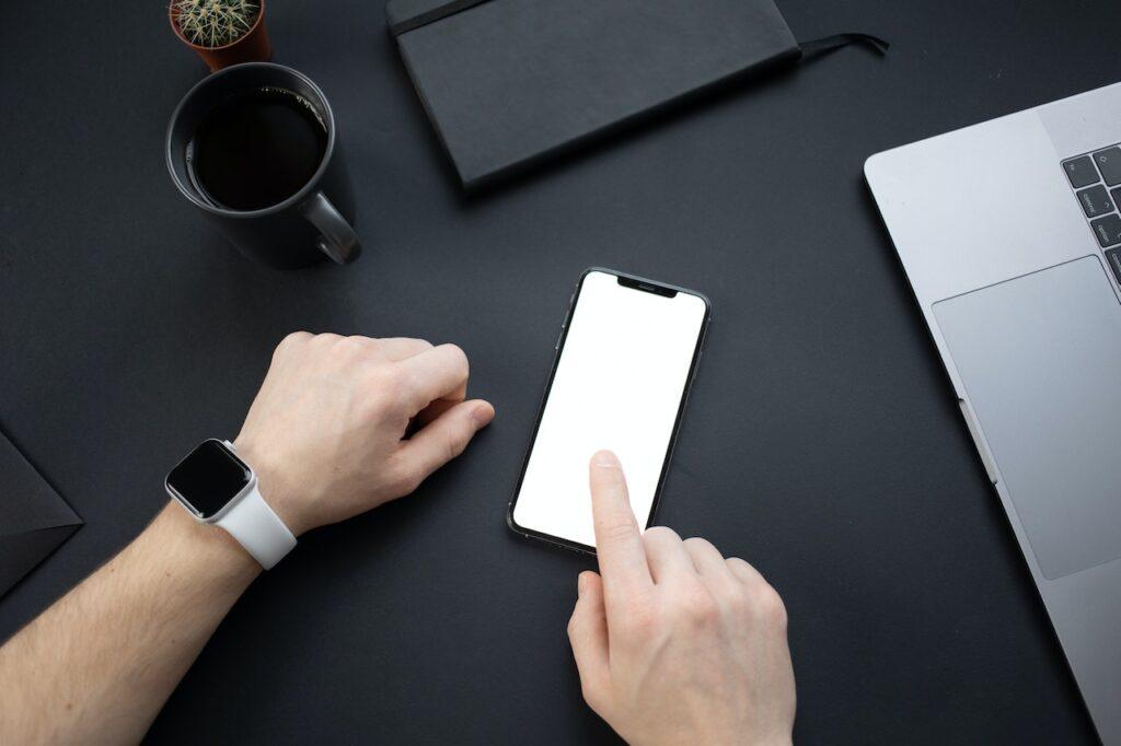 A Person Wearing a Smartwatch Touching the Blank Screen of a Smartphone