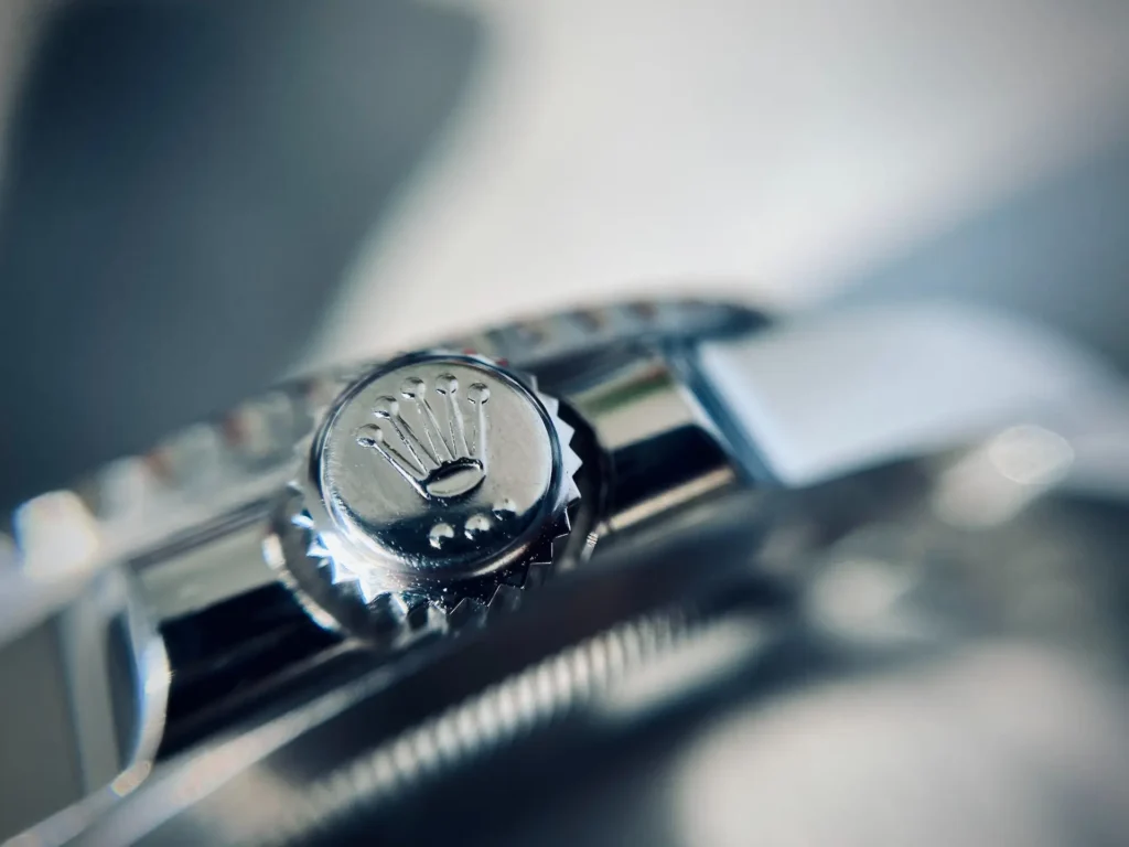 Close-up of a Rolex watch crown, featuring its iconic engraved crown logo.