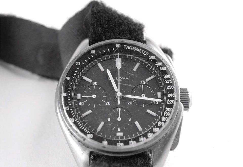 A close-up of a quality Bulova wristwatch featuring a black dial, three sub-dials, a tachymeter scale, and a worn leather strap, in black and white.