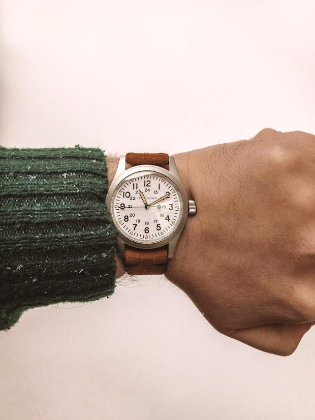 A close-up of a person's wrist wearing an white Hamilton Khaki Field Mechanical watch with a brown leather strap.