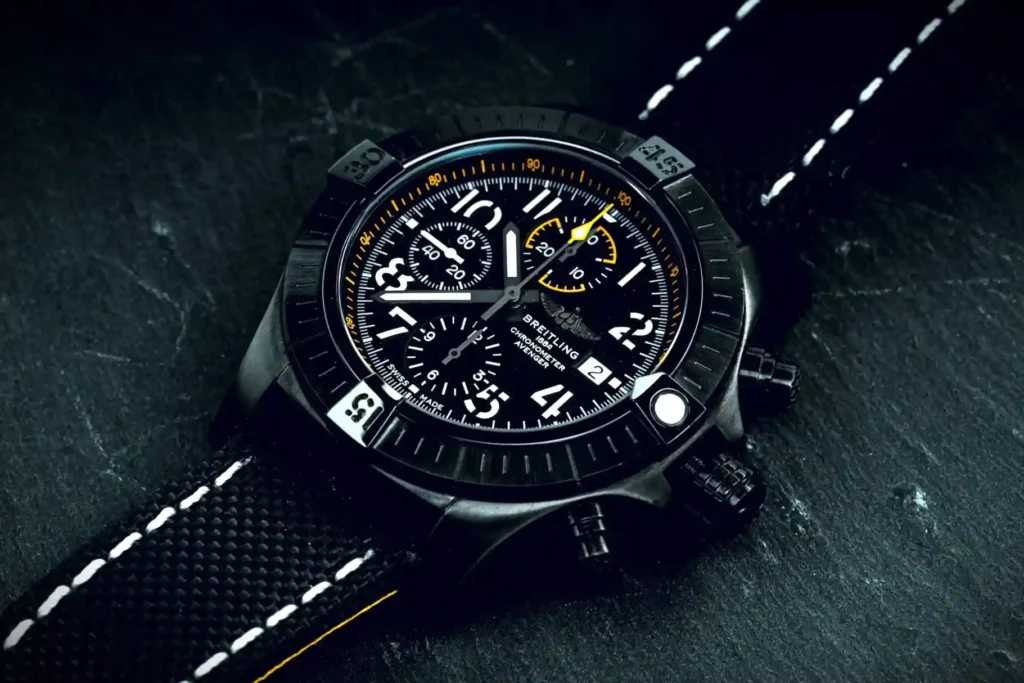 Close-up of a Breitling watch with a bold black dial and a stylish black stitched strap.