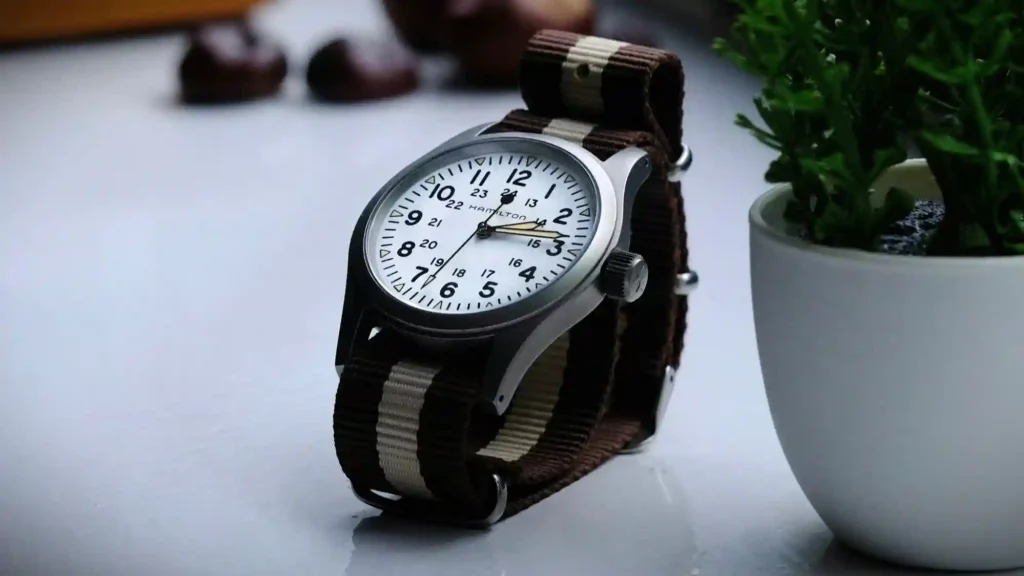 A Hamilton Khaki Field watch with a NATO strap is placed on a white table.