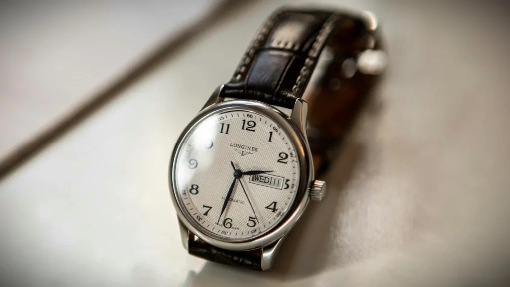 Close-up of a Longines watch with a sleek white dial and an elegant black leather strap.