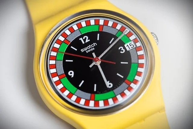 A Swatch watch with a yellow case and strap sitting on a white table.