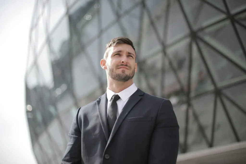 A man wearing a suit and tie stands outside a building.