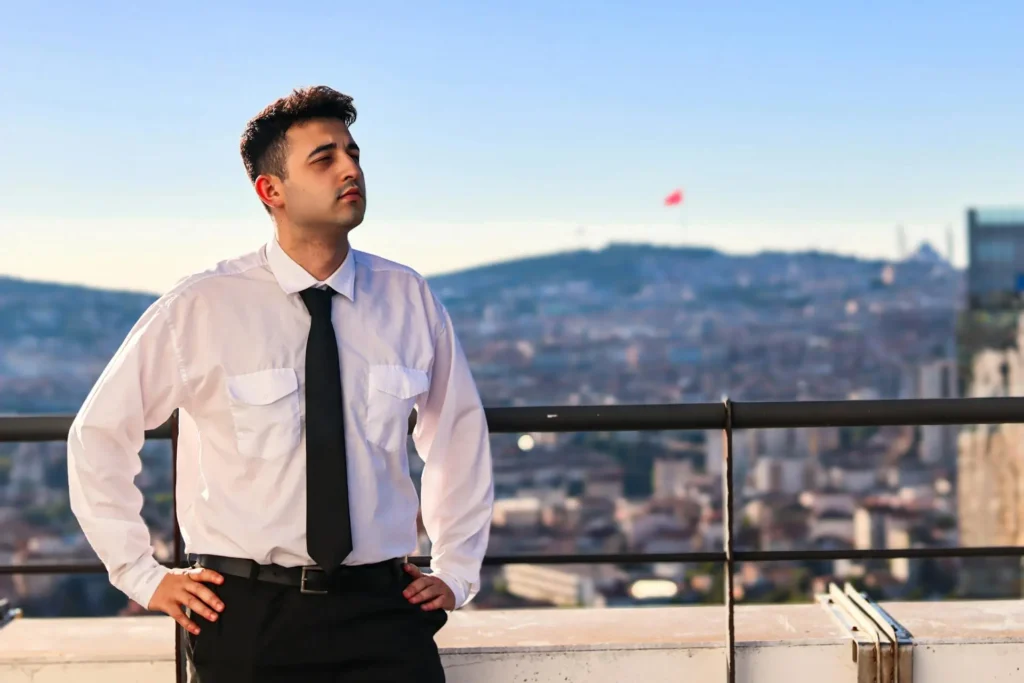 A man dressed in a white shirt and tie stands on a balcony.