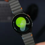 A person is holding a smart watch featuring a vibrant green face.