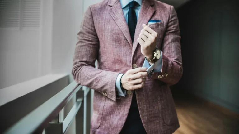 A man in a pink suit adjusts his watch