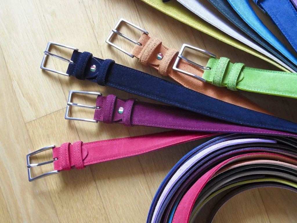 A collection of vibrant fabric belts displayed on a wooden floor.