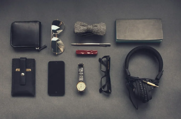 A collection of men's accessories: a watch, glasses, wallet, and headphones arranged stylishly on a flat surface.