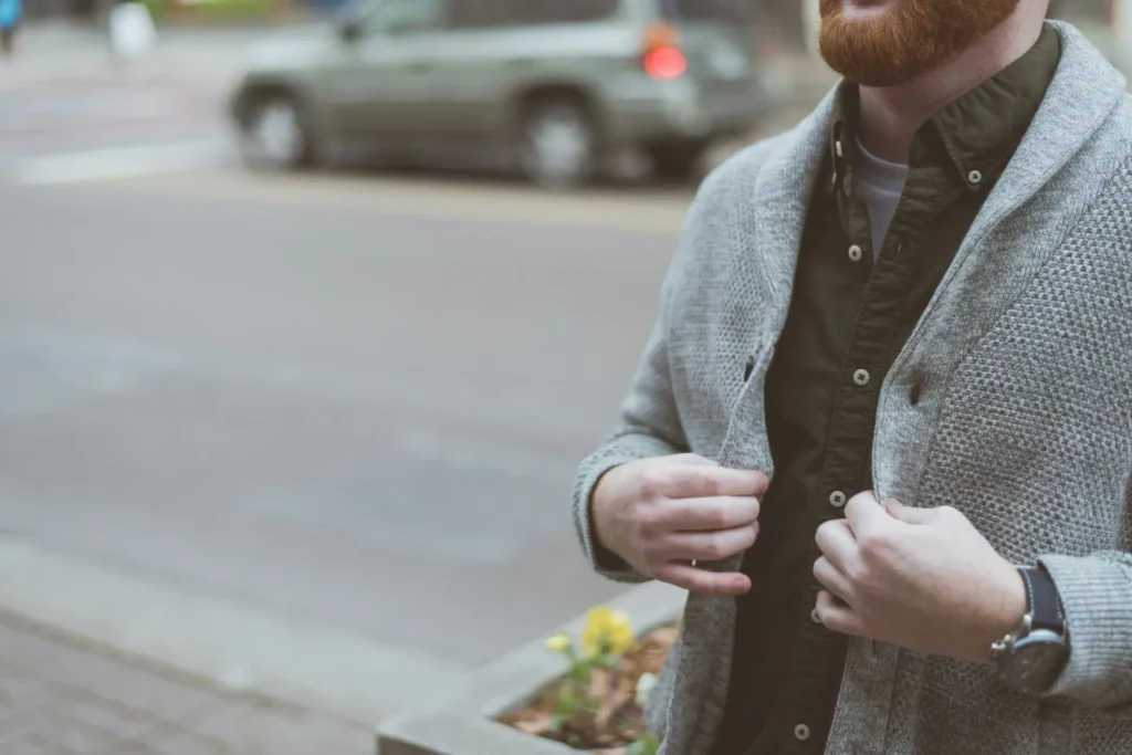 A bearded man wearing a cozy gray cardigan.