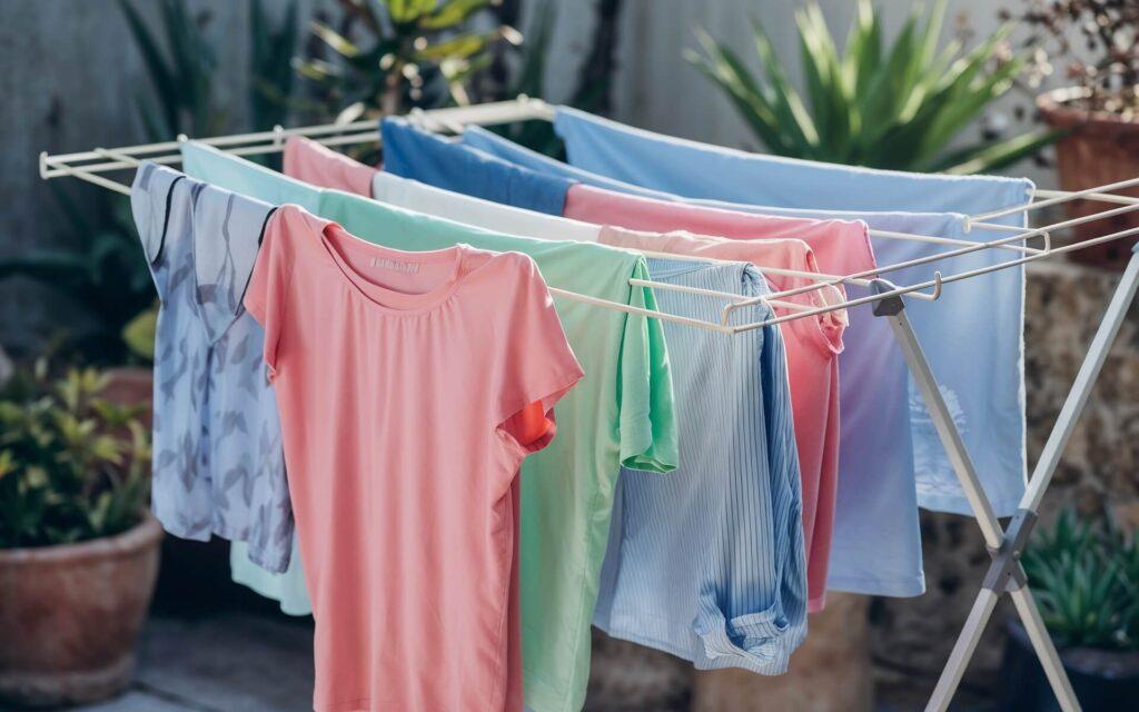 Freshly washed clothes drying on a rack in soft sunlight outdoors.