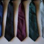 Five solid-colored neckties in navy blue, black, burgundy, forest green, and pale blue.