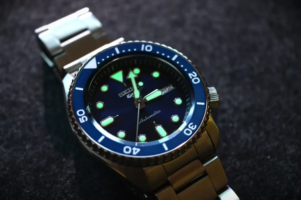 Close-up of a Seiko 5 dive watch featuring luminous hands and indices against a blue dial