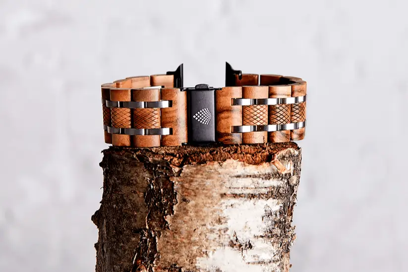 A stylish wooden watch band resting on a wooden block