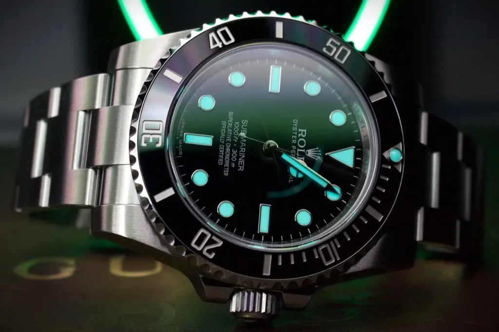 Close-up of a Rolex Submariner dive watch, highlighting its luminous hands and markers, along with the uni-directional bezel.