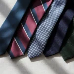 A professional display of five luxury men's ties, including classic and patterned styles, arranged on a light gray linen background—ideal choices for a polished job interview look.